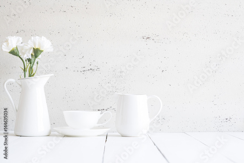 Interior with decorative vase and cup of tea on table top and white wood board