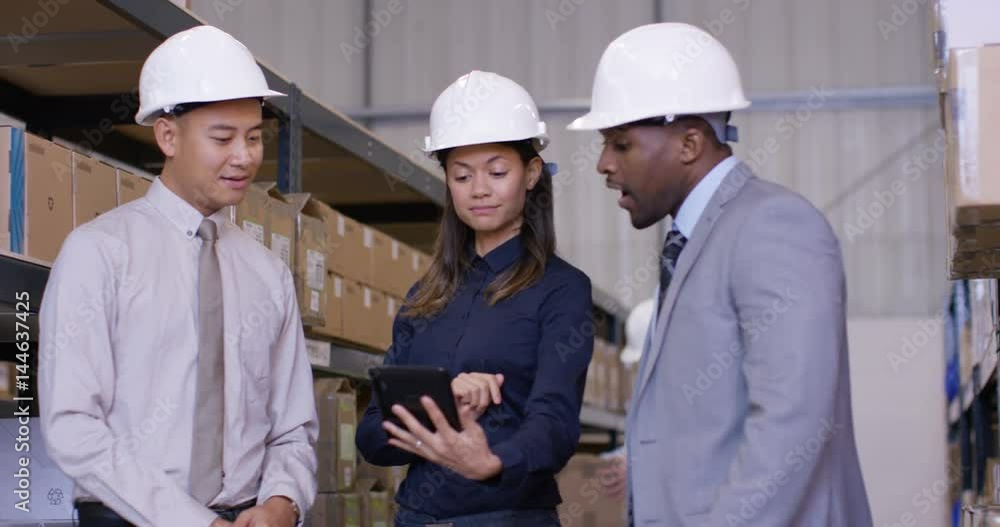 Mixed ethnicity management team in industrial warehouse shake hands on a deal Mixed ethnicity management team in industrial warehouse shake hands on a deal
