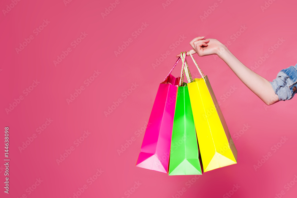 Female hand holding colorful shopping bags