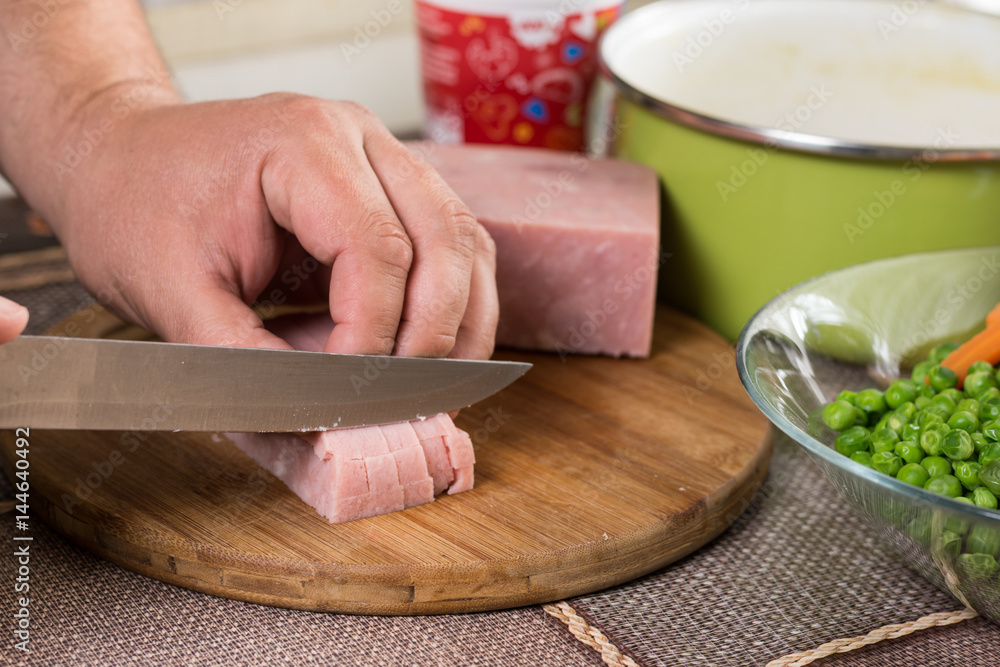 Cook chef slicing ham with ingredients in the background