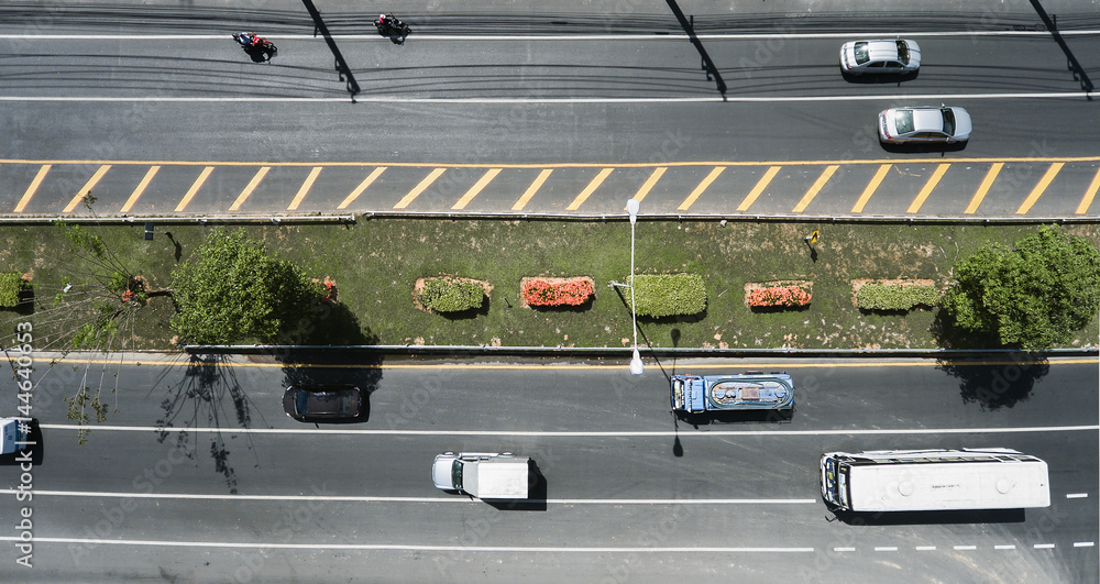 Aerial view of the wide road with a nice dividing strip of grass, flowers and trees..Top view of moving cars and buses..Flat illustration of road traffic. Aerial view of the wide road with a nice dividing strip of grass, flowers and trees..Top view of moving cars and buses..Flat illustration of road traffic.