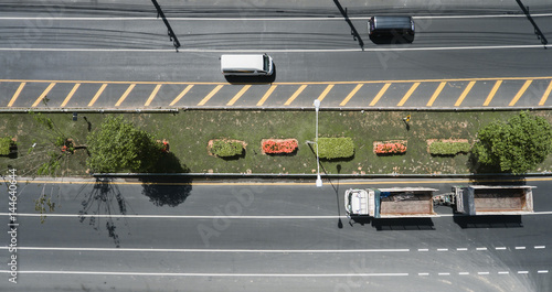 Aerial view of the wide road with a nice dividing strip of grass, flowers and trees..Top view of moving cars and trucks.Flat illustration of road traffic. photo