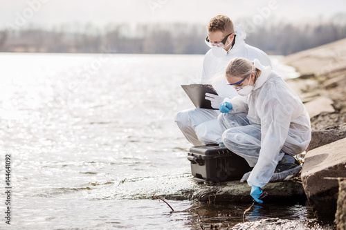 Scientists or biologists wearing protective uniforms working together on water analysis. . photo