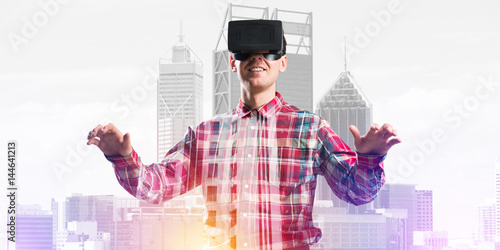 Guy wearing checked shirt and virtual mask stretching hands and trying to concentrate