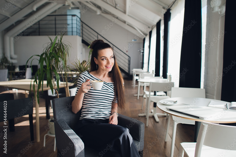 Portrait of an attractive adult woman with long straight hair holding a cup of coffee and looking away while sitting and enjoying the morning. Portrait of an attractive adult woman with long straight hair holding a cup of coffee and looking away while sitting and enjoying the morning.