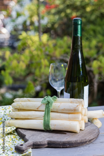 Fototapeta Naklejka Na Ścianę i Meble -  Spring food - fresh white big asparagus ready to cook on the table outside and garden view