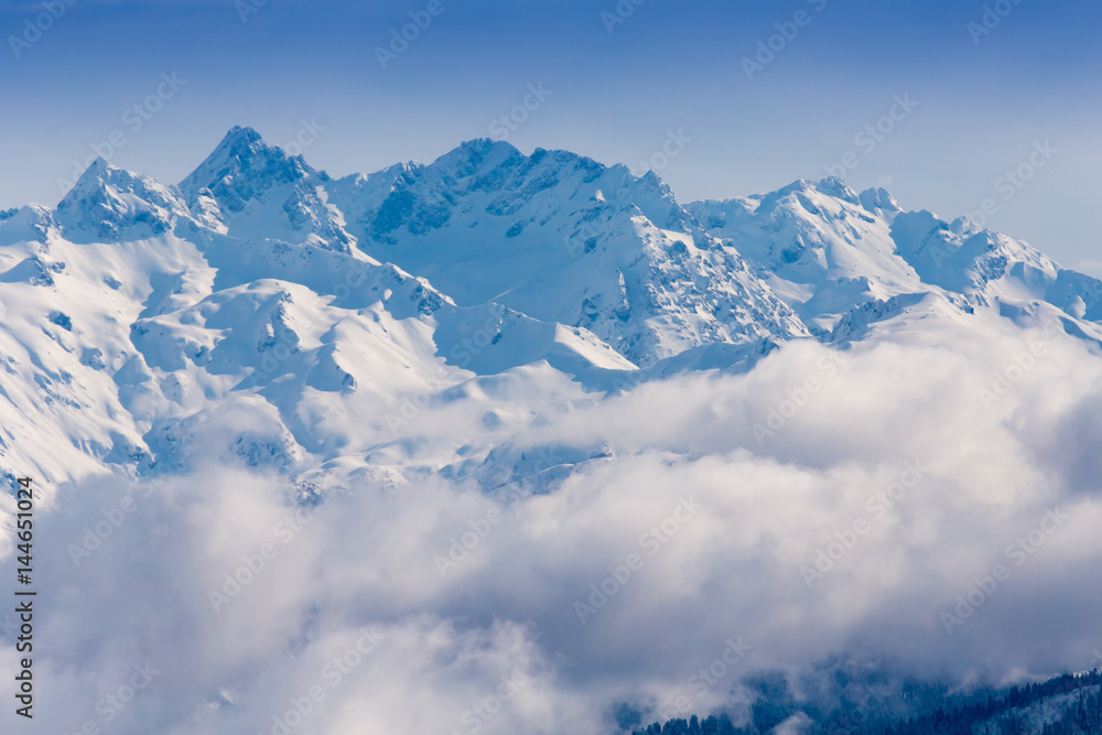 Snow mountains peaks covered by clouds on the sun Snow mountains peaks covered by clouds on the sun