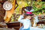 An little beautiful girl holding cylinder hat with ears like a rabbit over head at the table
