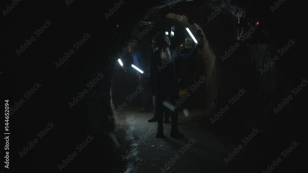 Team of potholers with hard hats and lamps exploring underground cave system Team of potholers with hard hats and lamps exploring underground cave system