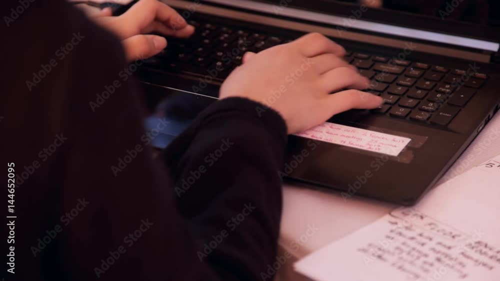 Women in a black sweater quickly prints on the keyboard at the laptop. Secretary of the head with both hands types the text after the meeting. There is a schematic outline for the preparation of the Women in a black sweater quickly prints on the keyboard at the laptop. Secretary of the head with both hands types the text after the meeting. There is a schematic outline for the preparation of the