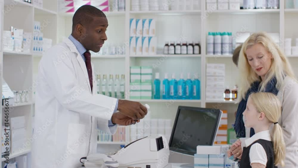 Worker in a chemist shop serving customers at the till. Worker in a chemist shop serving customers at the till.