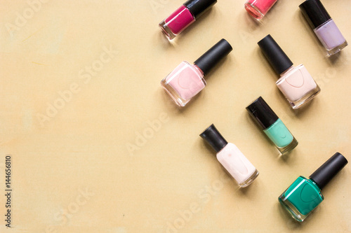 Bottles with nail polish over orange background top view mockup