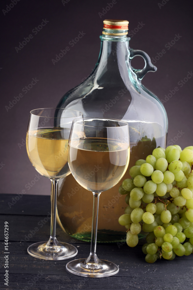 Bottle and glass of white wine, grape on wooden table