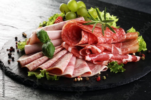 Food tray with delicious salami, pieces of sliced ham, sausage, tomatoes, salad and vegetable - Meat platter with selection