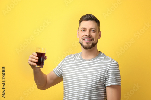 Handsome man posing with juice on color background