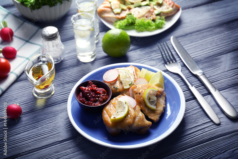 Plate of delicious tequila lime chicken with ingredients on wooden background Plate of delicious tequila lime chicken with ingredients on wooden background