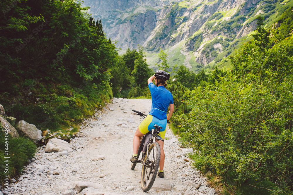 girl on a Bicycle travels to Slovakia. black helmet, blue shirt, mountains, high Tatras,