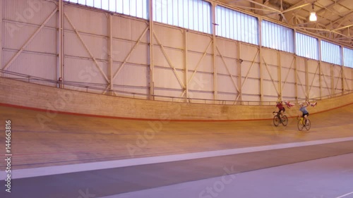  Cyclists on racing track in velodrome doing victory lap with flags photo