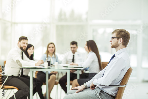 Manager sitting in an office chair in the background of business team working at Desk