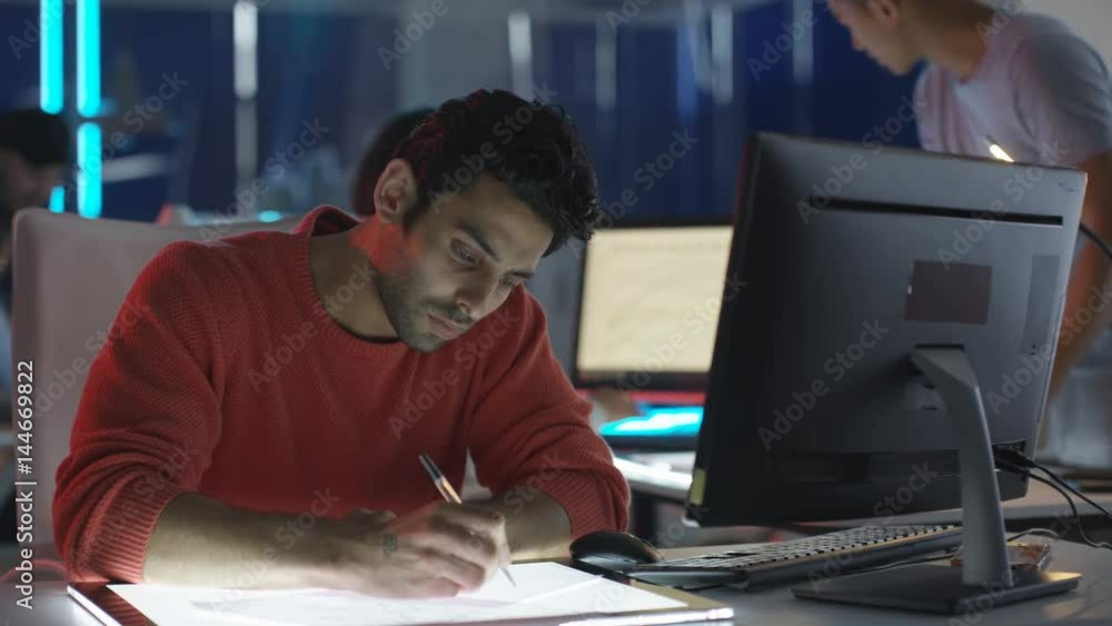 Portrait smiling young computer game designer drawing at his desk. Portrait smiling young computer game designer drawing at his desk.