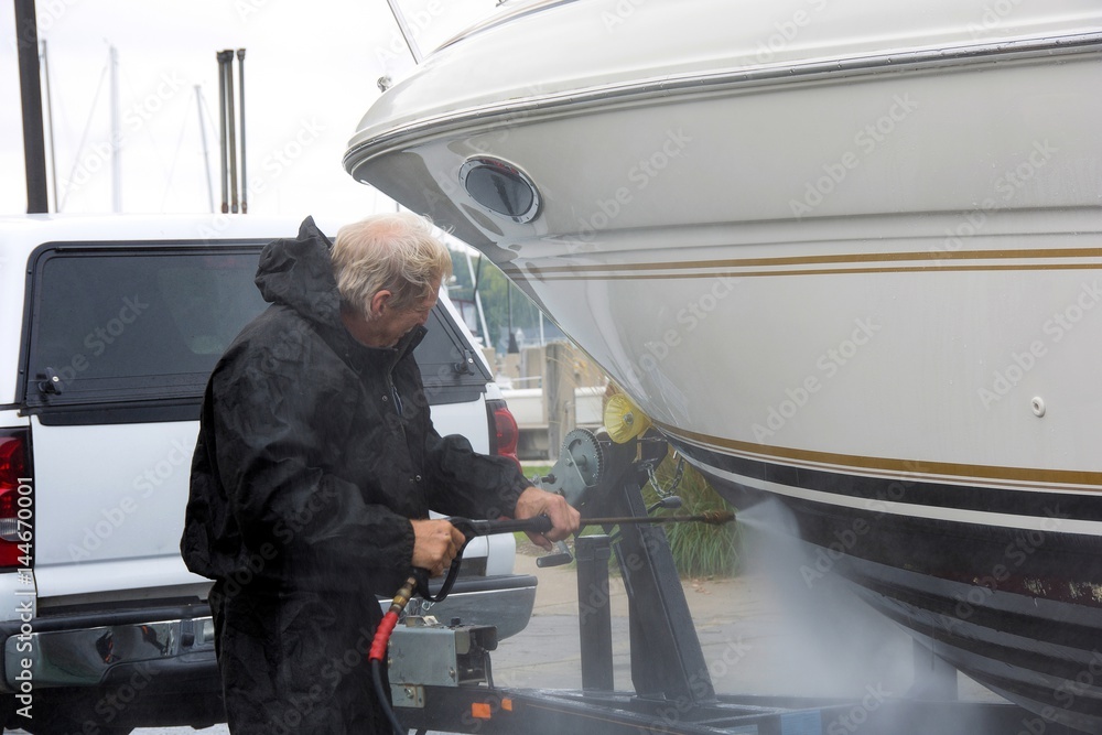 Caucasian man pressure washing a boat hull