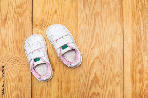a pair of baby sneakers on wood background