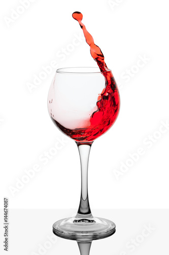 Splash of red wine in the cup filling on a white background