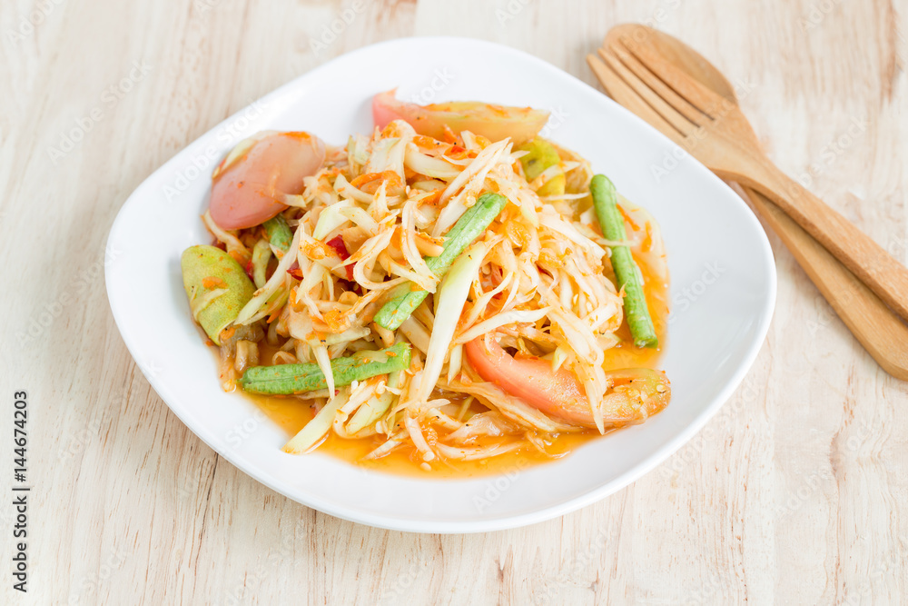 Papaya salad in a white plate on a wooden table,Local thai food
