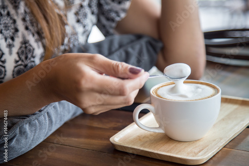 cup of capuchino coffee with woman and spoon