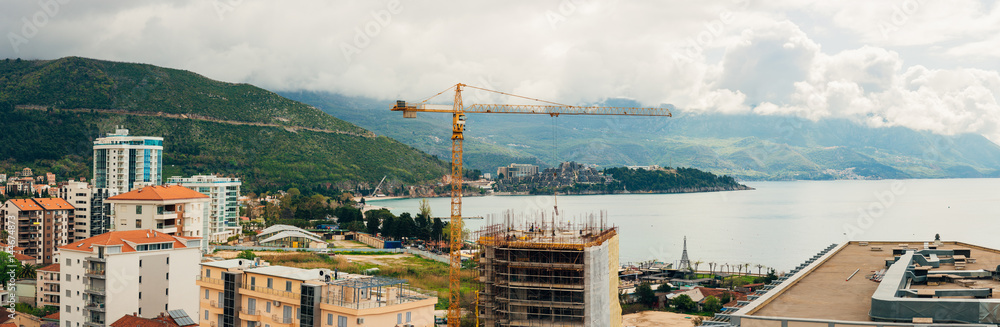 Construction of a multistory building in Budva, Montenegro. Builders are building a house. Crane working at a construction site. Sticks reinforcement of concrete.