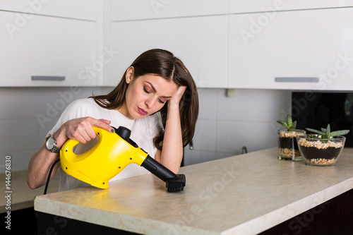 Woman cleaning kitchen with steam cleaner