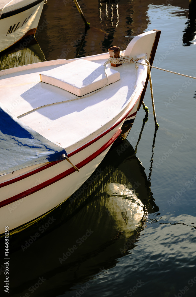 boat and reflection, close up of a small boat anchored that reflect itself on the sea