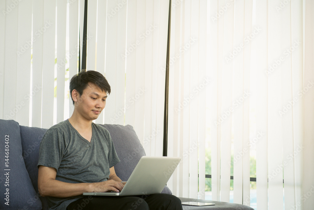 Goodlooking young man relaxing at home in armchair, sitting in living room with laptop computer, smiling. Goodlooking young man relaxing at home in armchair, sitting in living room with laptop computer, smiling.