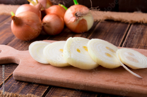 Onion slices on rustic wooden table background.