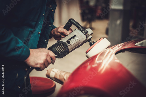 Mechanic polishning car body details in restoration workshop © Nejron Photo