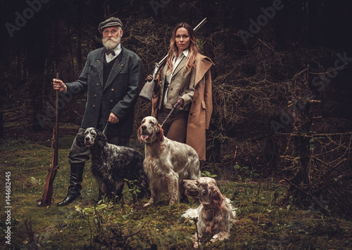 Canvas Print Two hunters with dogs and shotguns in a traditional shooting clothing