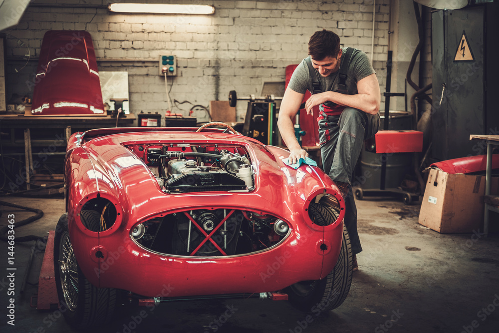 Mechanic polishning car in restoration workshop
