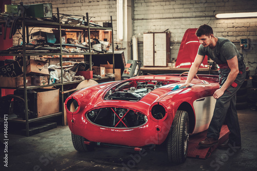 Foto Mechanic polishning car in restoration workshop