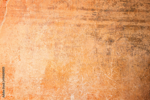 Weathered, aged and scratched orange concrete wall texture background with vignetting.