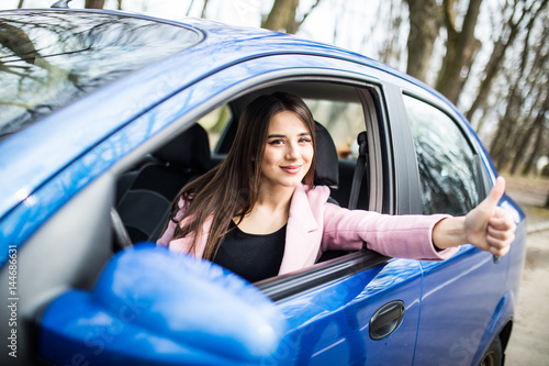 Woman sitting in the car and showing thumbs up on road