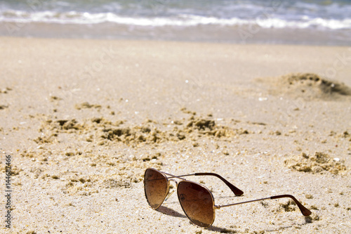 Sunglasses on sand beach with sea background