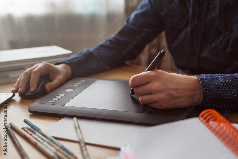 Workplace of designer. Graphic tablet surrounded by phone, camera, pencils and books. Illustrator draws a sketch Workplace of designer. Graphic tablet surrounded by phone, camera, pencils and books. Illustrator draws a sketch