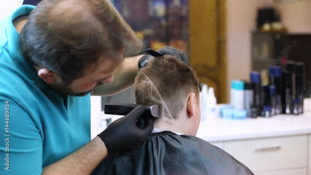 Barber makes a fashionable man's haircut to the client Barber makes a fashionable man's haircut to the client