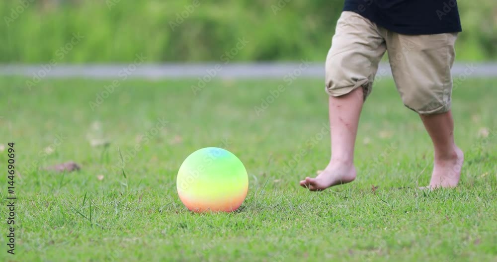 Happy asian boy playing soccer football in the garden on a bright summer day. Happy asian boy playing soccer football in the garden on a bright summer day.
