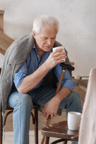 Cheerless aged man holding a cup