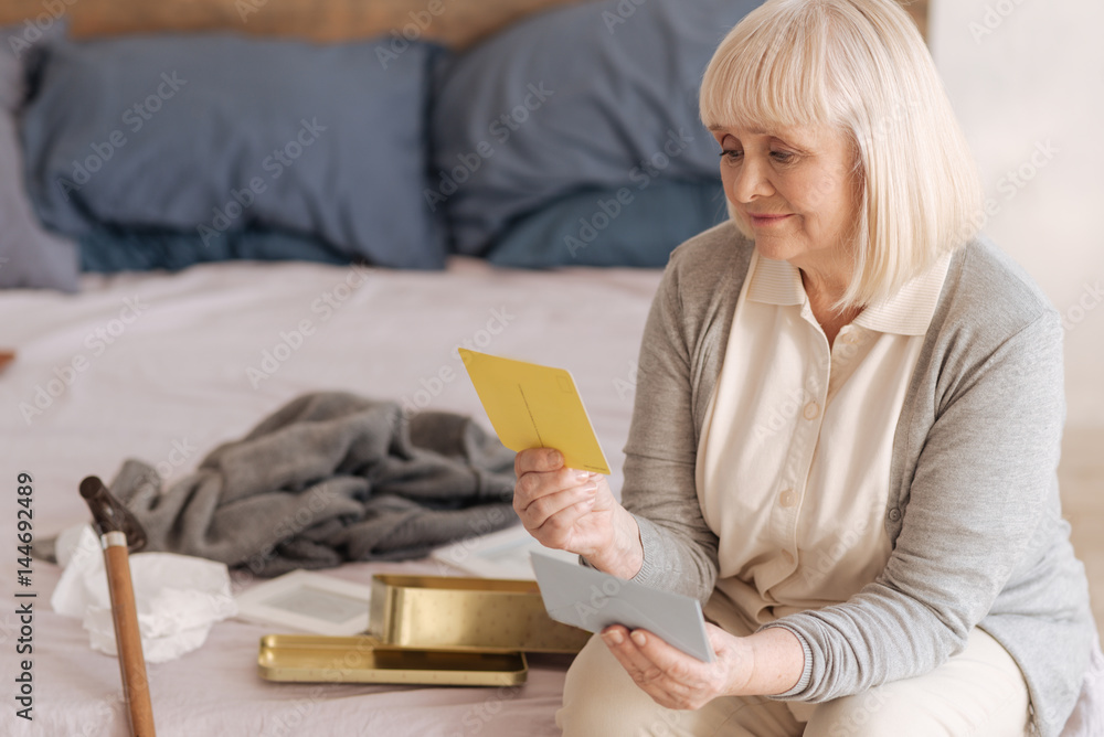 Sad cheerless woman looking at the old postcard Sad cheerless woman looking at the old postcard