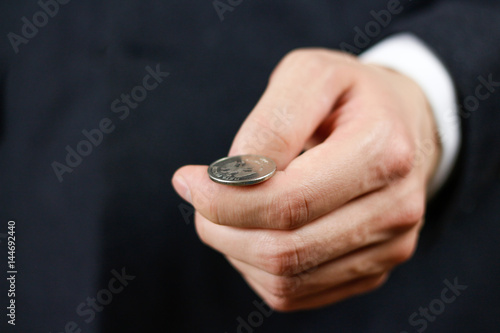 Businessman tossing a coin. Heads or tails. Close up photo