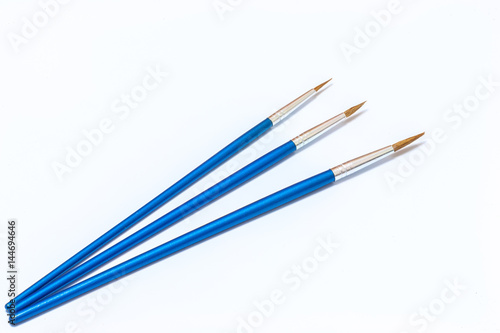 Three blue paint brushes on a white background