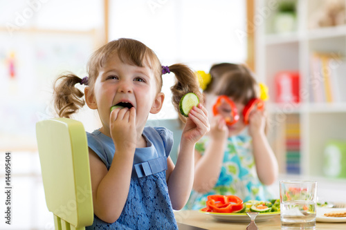 children eating vegetables in kindergarten or at home
