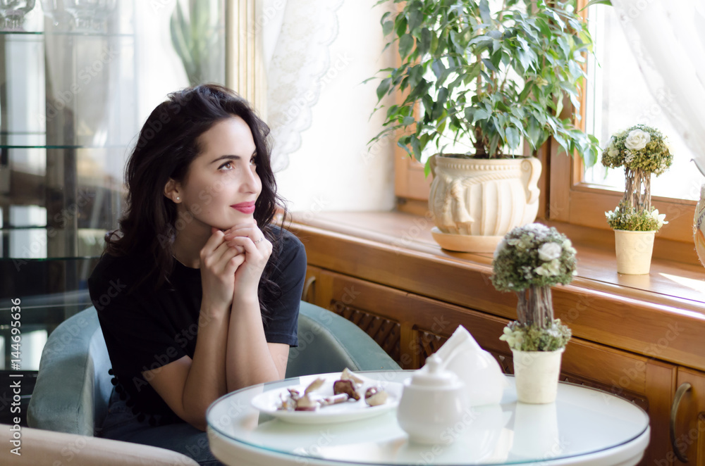Young attractive woman has a coffee break, sitting in cafe with beautiful interior and enjoying the moment Young attractive woman has a coffee break, sitting in cafe with beautiful interior and enjoying the moment